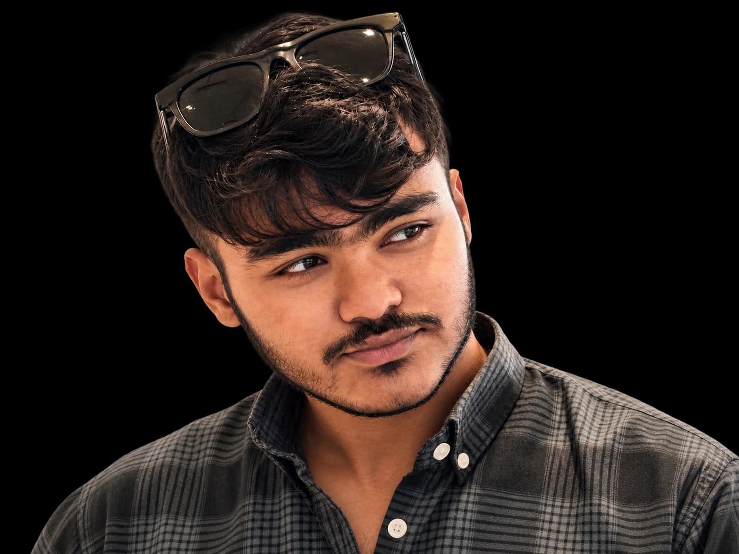 Mohammad Awais wearing a charcoal checked shirt with sunglasses resting on his hair